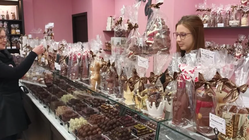 Intérieur de la chocolaterie Beussent Lachelle avec mur rose, ballotins en cellophane et vitrine de chocolats pralinés