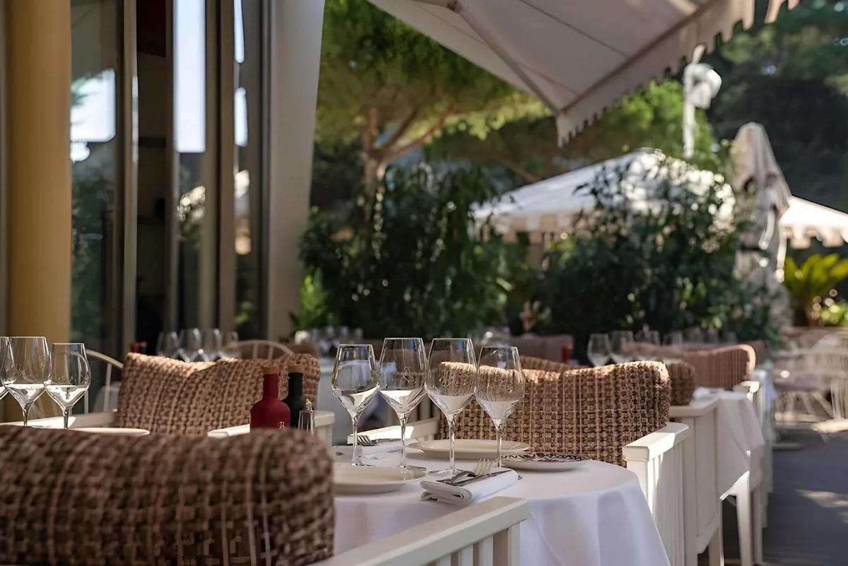 Terrasse ombragée du restaurant Brigitte à La Baule avec tables dressées, vaisselle élégante et nappes blanches