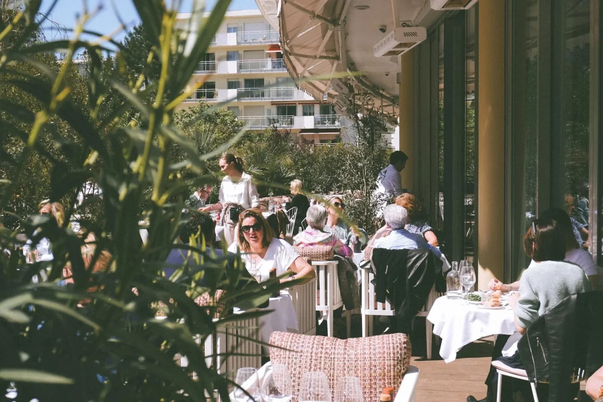 Terrasse animée du restaurant Brigitte à La Baule un jour ensoleillé, parasols blancs et clientèle attablée
