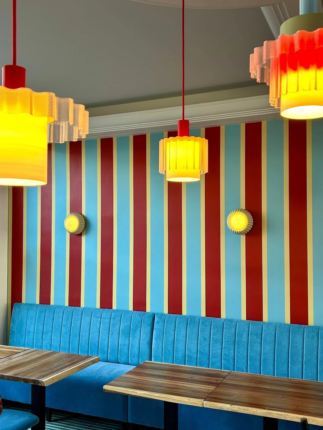 Banquette velours bleue et mur rayé rouge-bleu au Café de la plage