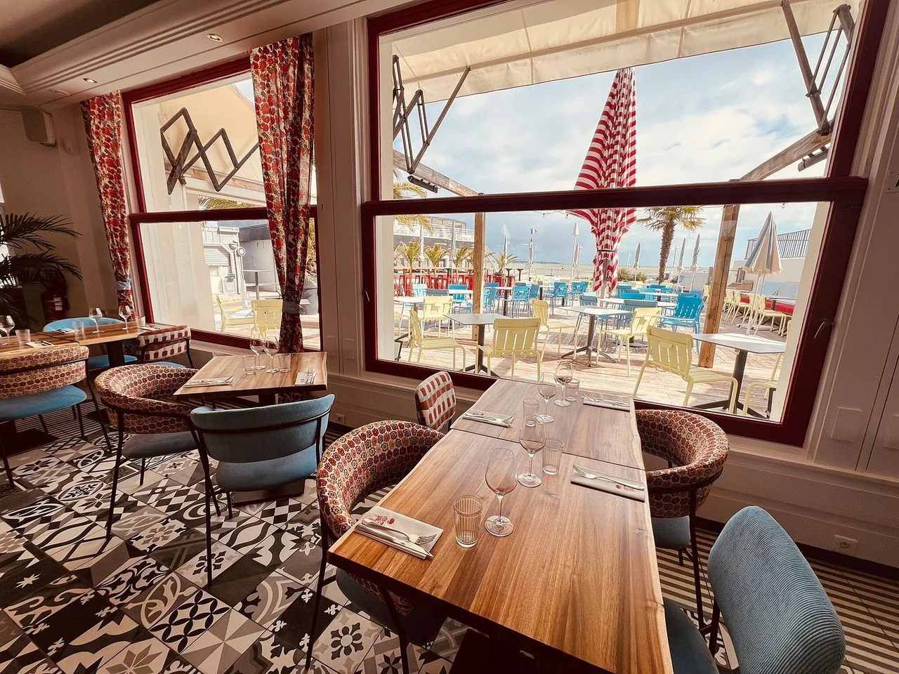 Salle du Café de la plage avec carrelage à motifs noir et blanc et vue sur la terrasse