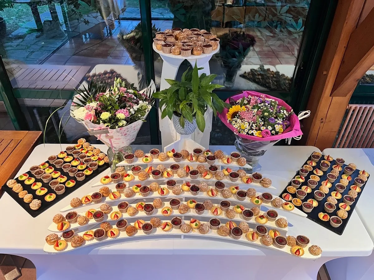 Buffet de mignardises et pâtisseries dressé sur table blanche avec bouquets de fleurs · événement privé