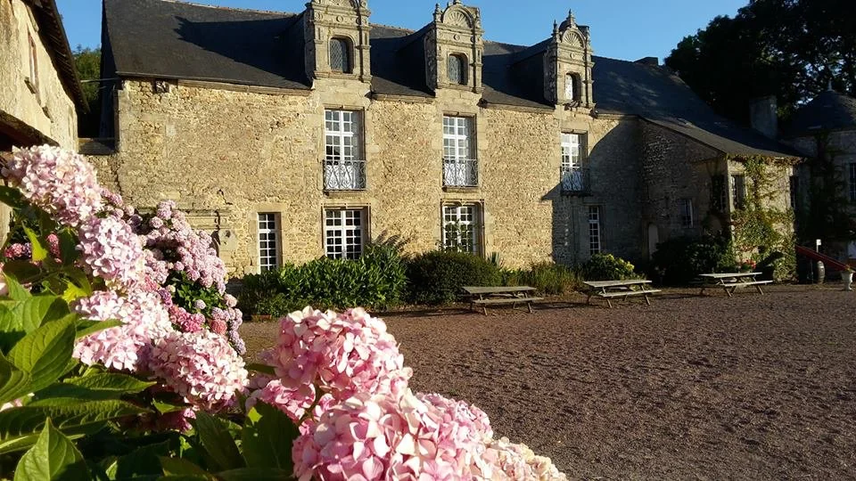 Façade du Château de Careil au coucher du soleil avec hortensias roses au premier plan
