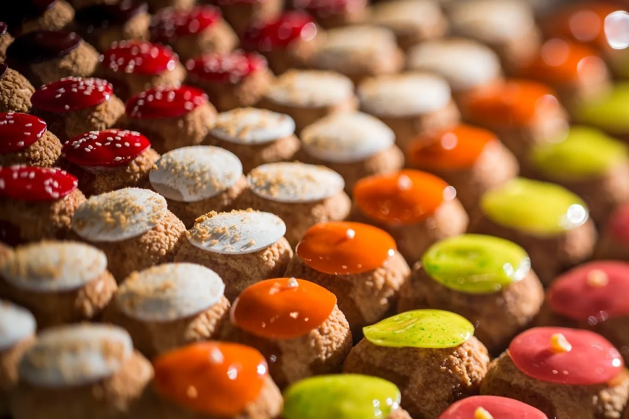 Gros plan sur des petits gâteaux glacés colorés à la Pâtisserie Emma