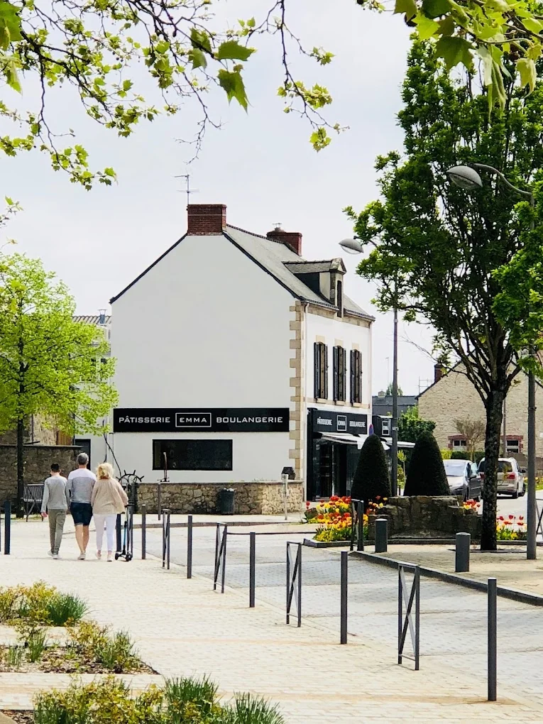 Façade de la Pâtisserie Emma vue depuis la place avec arbres et stationnements
