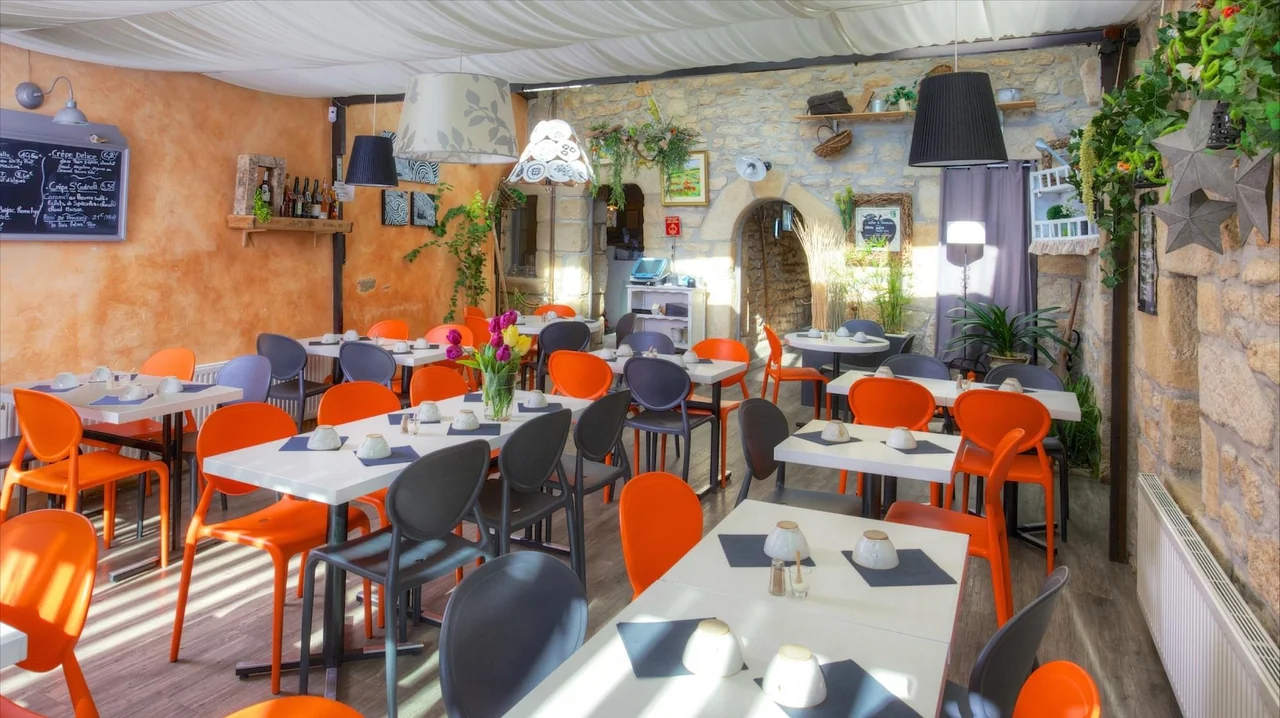 Salle de la Crêperie Fleur de Sel avec murs en pierre et chaises orange et anthracite