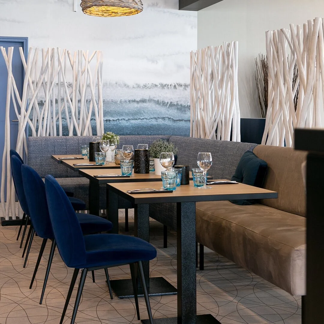 Banquettes et tables de La Flottille avec mur en bois flotté décoratif