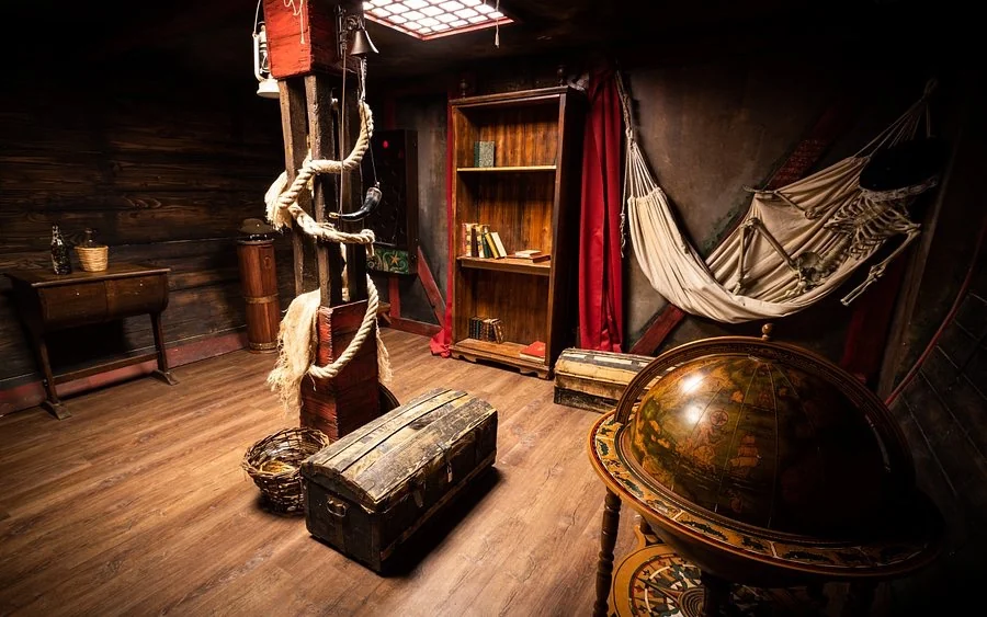 Intérieur d'une salle d'escape game au Hangar de La Baule, décor bateau pirate avec coffres et globe terrestre