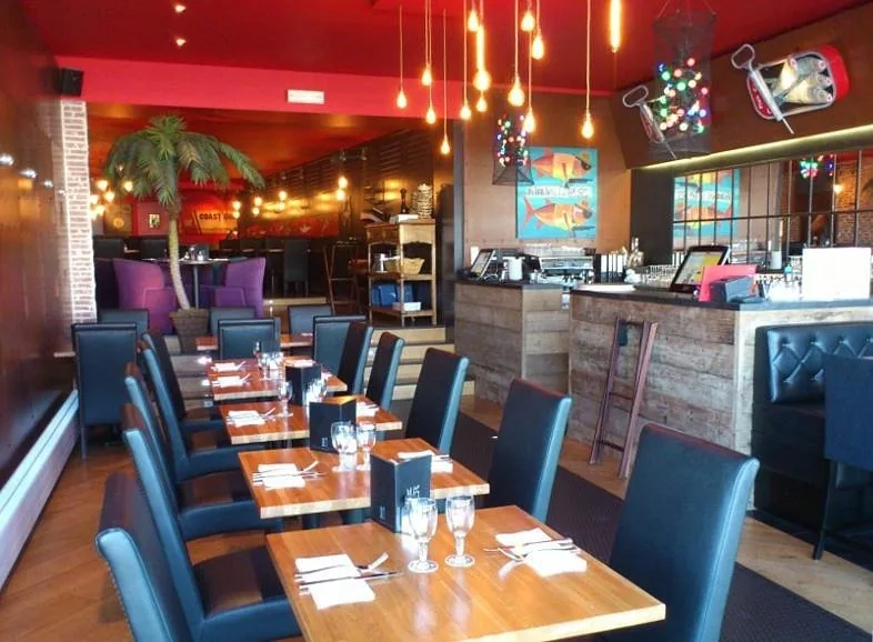 Salle intérieure du Café Jules avec décor coloré, palmiers et tables prêtes pour le service