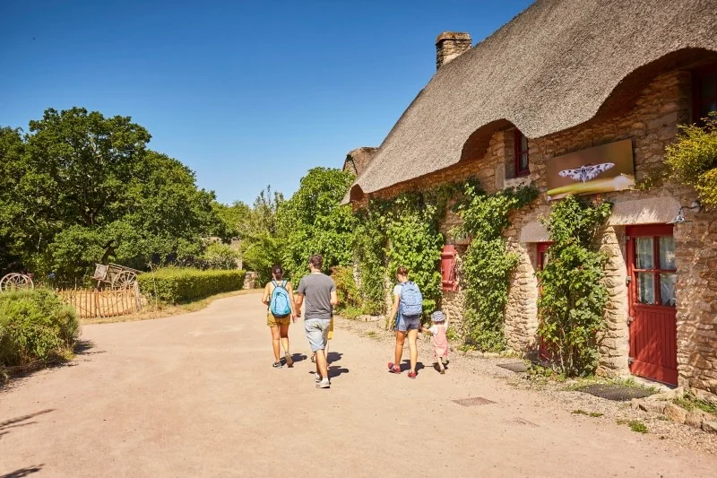 Famille promenant devant une chaumière du village de Kerhinet en Brière