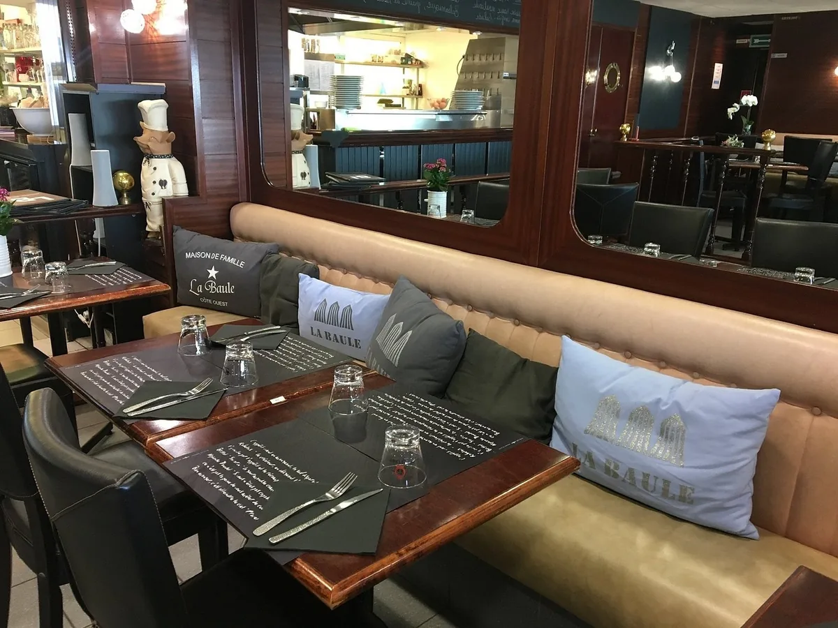 Intérieur cosy du LB Mer avec banquette en cuir camel et coussins brodés 'La Baule'