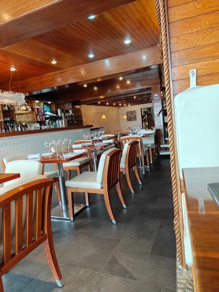 Intérieur du restaurant Le Lénigo au Croisic avec ses boiseries vernies, chaises en cuir blanc et ambiance bateau-chic