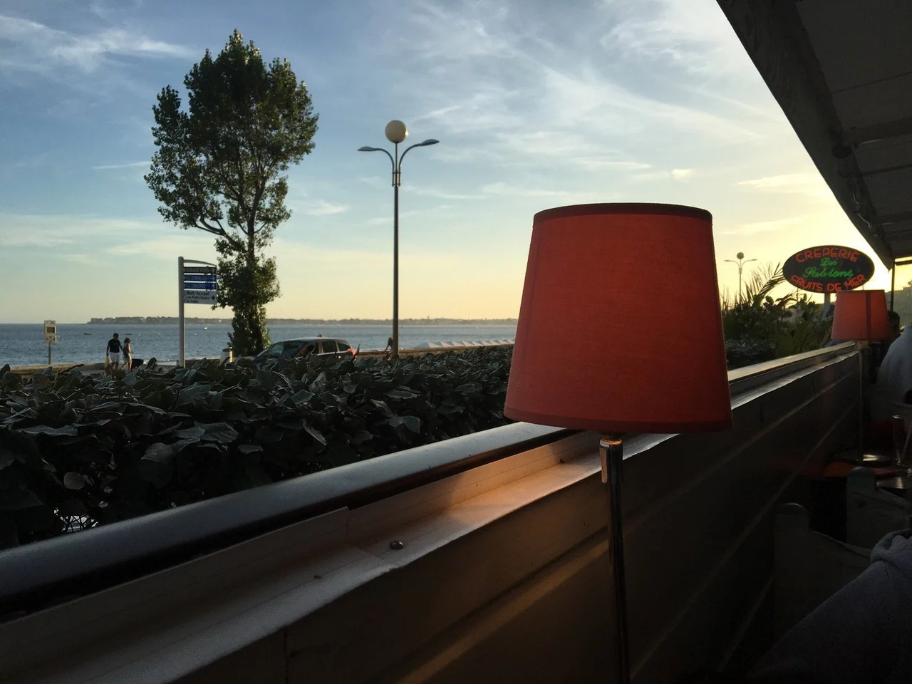 Enseigne lumineuse Crêperie Les Sablons au coucher du soleil avec lampe rouge en bord de terrasse