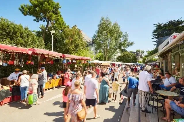 Marché de plein air animé dans une rue de La Baule, étals et petit train touristique