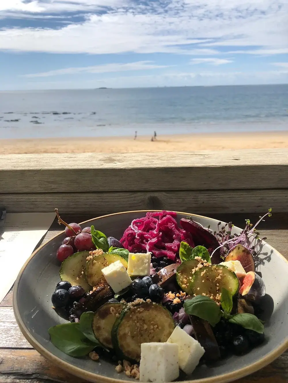 Bowl gourmand de courgettes, feta, figues, raisins et chou rouge servi face à la plage de Pornichet